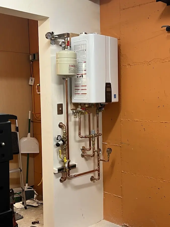 Plumbing technician inspecting water heater connections in Au Sable